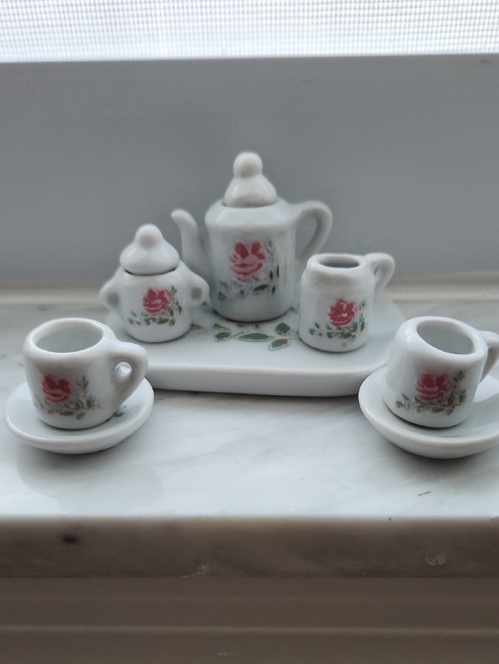 Miniature white porcelain tea set pieces, featuring pink rose floral patterns